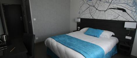 A hotel room with a bed, a desk, and a chair.