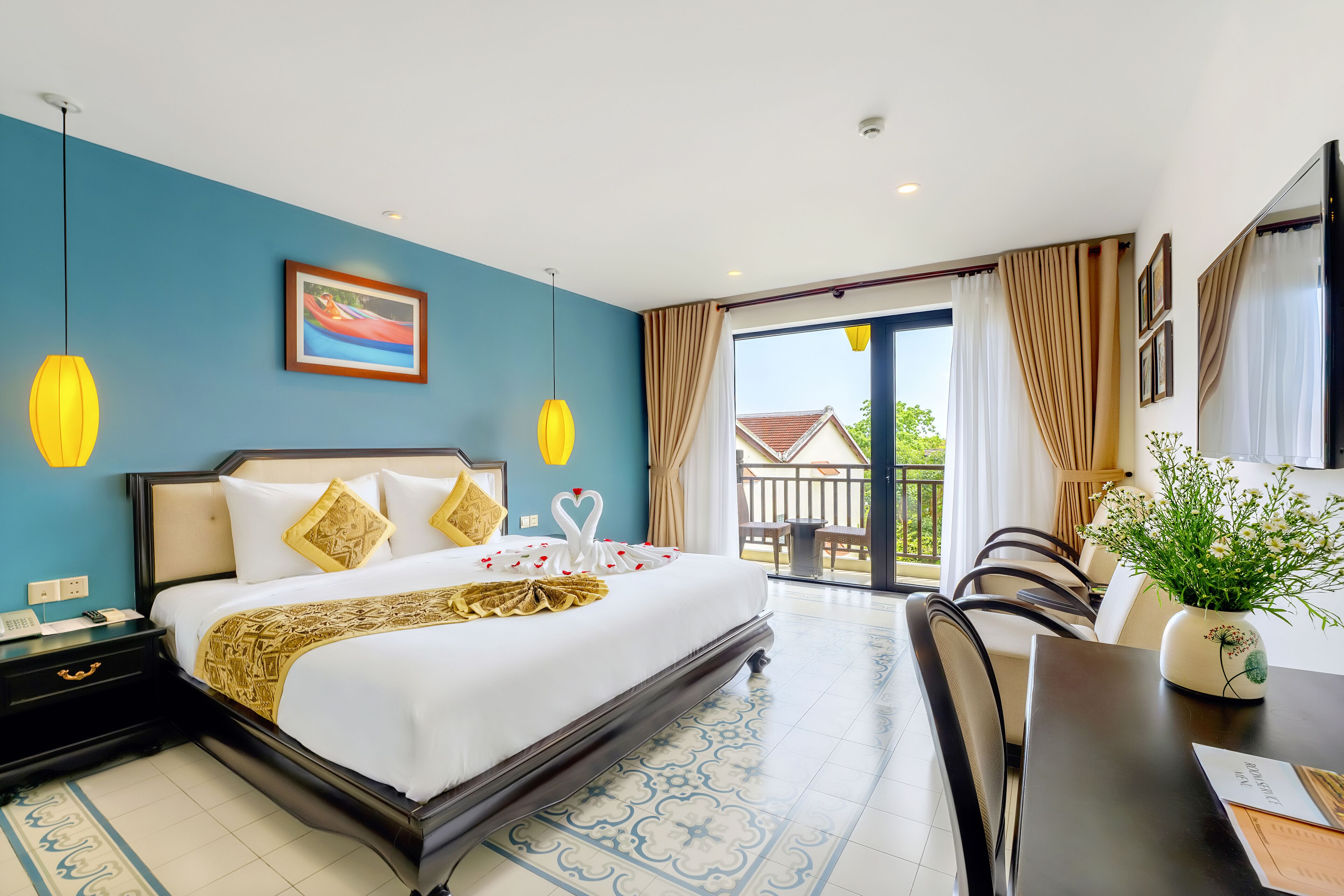 A hotel room with a large bed, a desk, and a view of the outside.