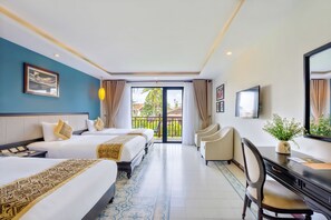 Une chambre d’hôtel avec deux lits, un bureau, une chaise, une télévision et un balcon donnant sur un espace verdoyant.