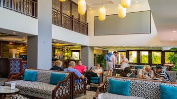 A spacious lobby with multiple seating areas, a bar, and a staircase leading to an upper level.
