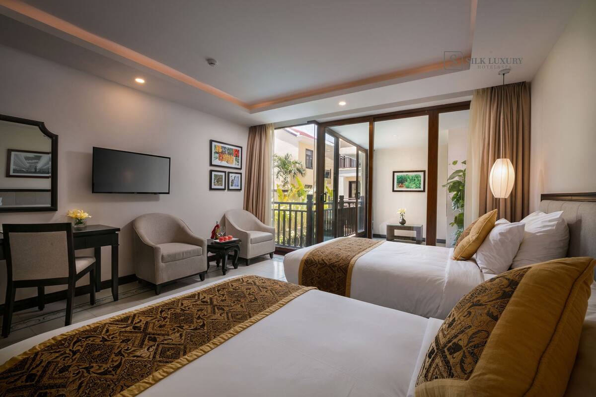 A hotel room with two beds, a TV, a desk, and a chair.