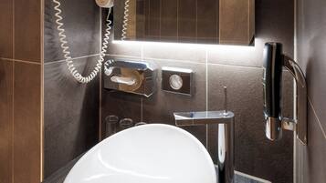 Un baño moderno con un lavabo blanco, un secador de pelo y un espejo.