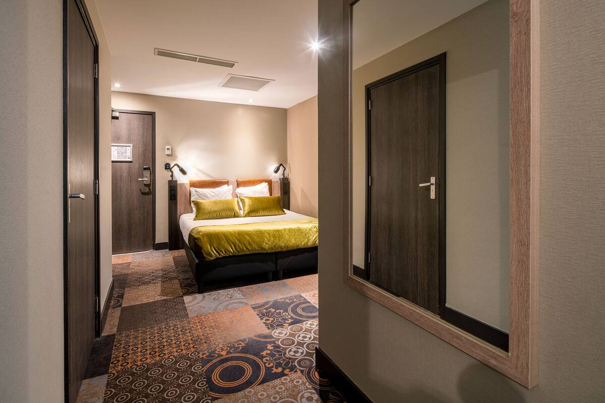 Ett hotellrum med en säng, en garderob och en mönstrad matta.