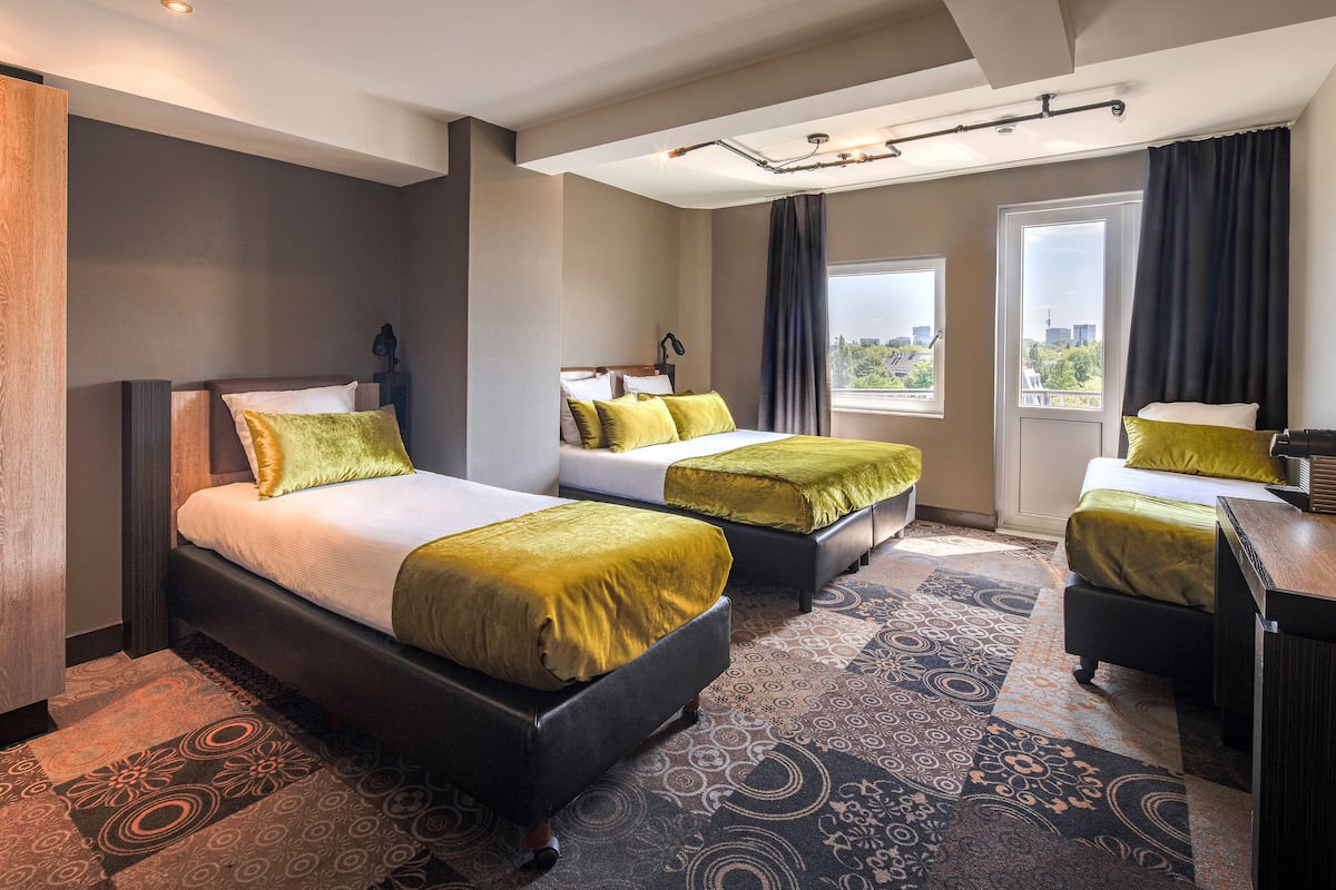 Ett hotellrum med två sängar, ett skrivbord och ett stort fönster med utsikt över staden.