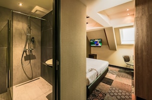 Une chambre d’hôtel moderne équipée d’une douche, d’un lit, d’une télévision et d’une fenêtre.