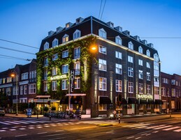 A hotel with a dark facade, ivy-covered exterior, and multiple windows.