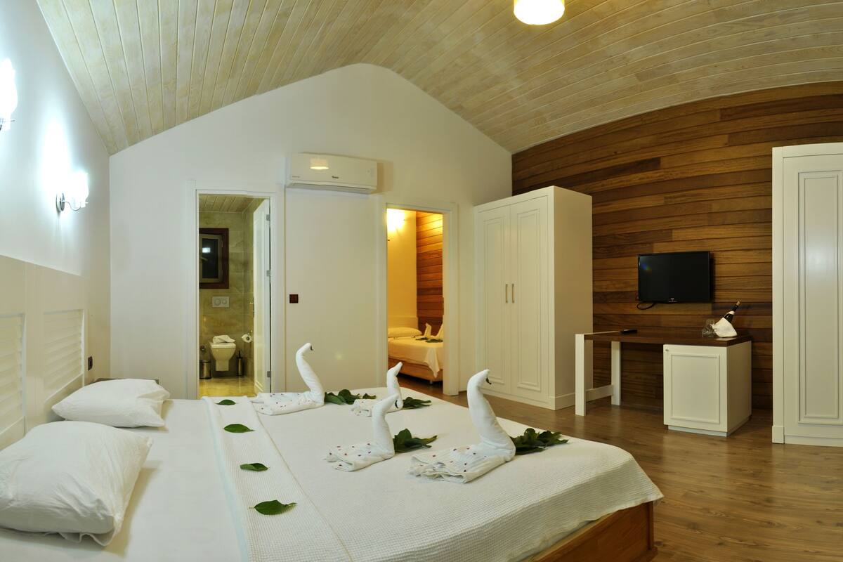 A bedroom with a bed, a wooden ceiling, a television, and a wardrobe.