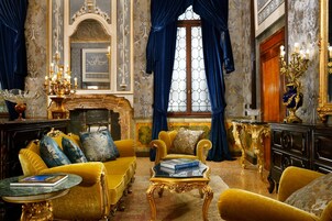 Quarto luxuoso com lareira, móveis ornamentados e um espelho grande.