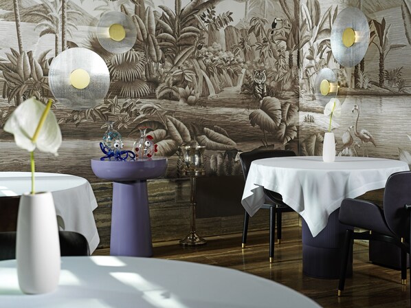 A dining area with round tables, a purple pedestal table, and a mural of a tropical scene. - Palazzo Venart Luxury Hotel (Venice)