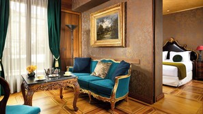 Una habitación con un sofá color turquesa, una mesa de centro de madera, un cuadro en la pared y una cama con cabecera negra.