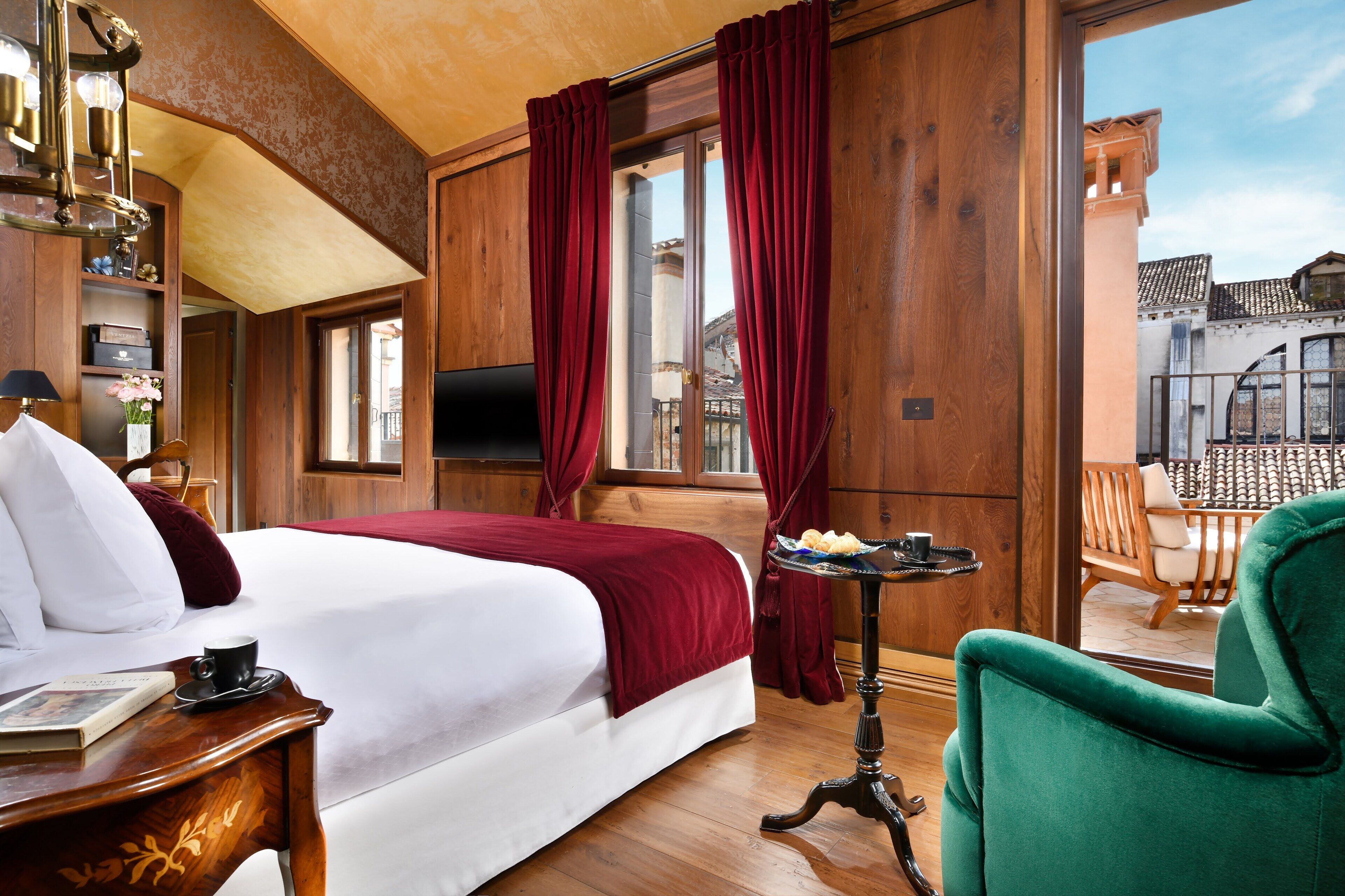 A hotel room with a large bed, wooden walls, a balcony with a chair, and a television.