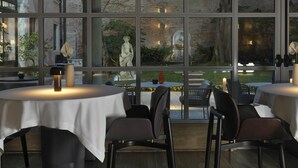 Un restaurant avec de grandes fenêtres, des tables rondes et des chaises.