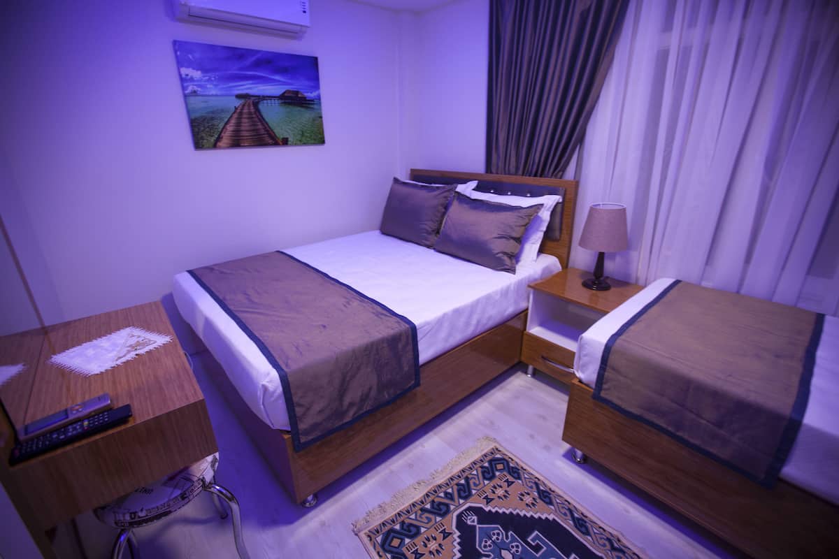 Una habitación de hotel con cama, mesita de noche, lámpara y alfombra.