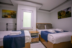 A hotel room with two beds, a window, and artwork on the walls.