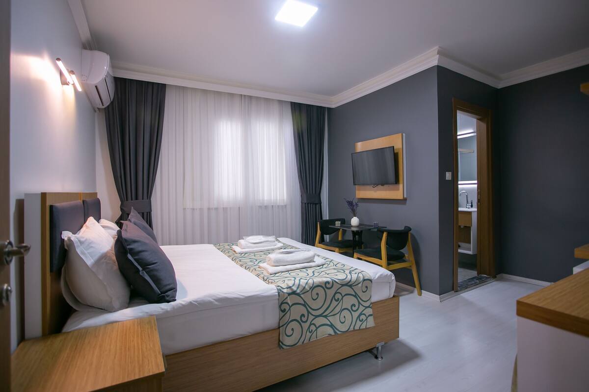Habitación de hotel con cama, mesita de noche, televisión y escritorio con silla.