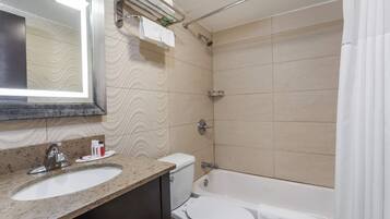 Un baño con lavamanos, inodoro, bañera y espejo con luz.