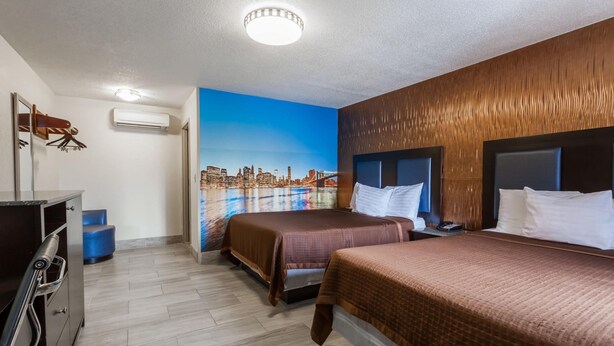 Ett hotellrum med två sängar, en väggmålning som föreställer en stadsbild, en sänggavel i trä och ett skrivbord med en spegel.