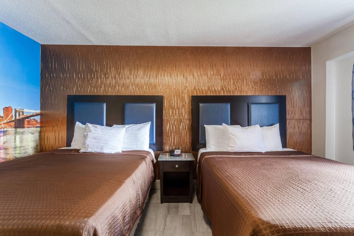Habitación de hotel con dos camas, una mesita de noche y vistas a un puente.