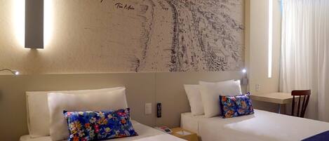 A hotel room with two beds, a wall mural, a small table, and a chair.