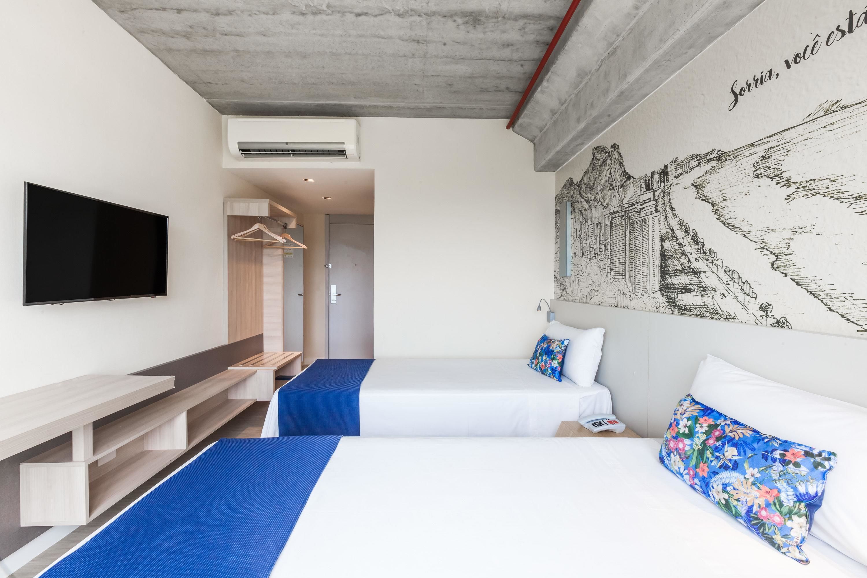 Habitación de hotel con cama, televisor, escritorio y armario.