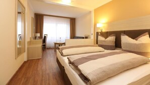 A hotel room with two beds, a desk, a chair, a mirror, and a window with curtains. - Hotel am Westend (Lahr)