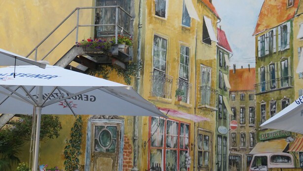 A street scene with buildings, outdoor seating, and a parked vehicle. - Hotel am Westend (Lahr)