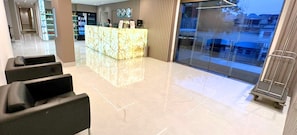 A hotel lobby with a reception desk, seating area, and large windows. - Hotel Arujá (Aruja)