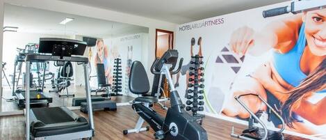 Une salle de sport équipée de tapis de course, de vélos elliptiques et d’appareils de musculation.