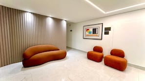 Un hall d’entrée moderne avec un canapé incurvé, une œuvre d’art accrochée au mur et un sol carrelé.