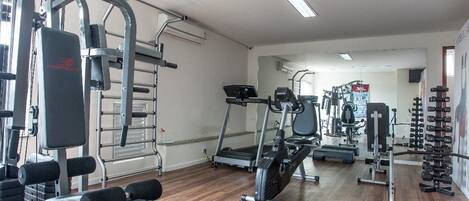 Un gimnasio con diversos equipos de ejercicio, incluyendo cintas de correr, máquinas de pesas y pesas libres.