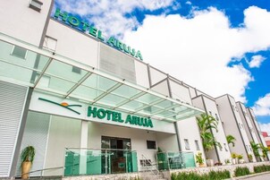 Um hotel moderno com fachada de vidro e o nome "HOTEL ARUJA" em destaque.