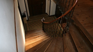 A wooden staircase with a handrail, leading to a room with patterned flooring. - Le Voltaire Chambres et Table d'Hotes (Airvault)