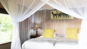 A bedroom with a bed, a nightstand, a lamp, and a painting of deer on the wall.