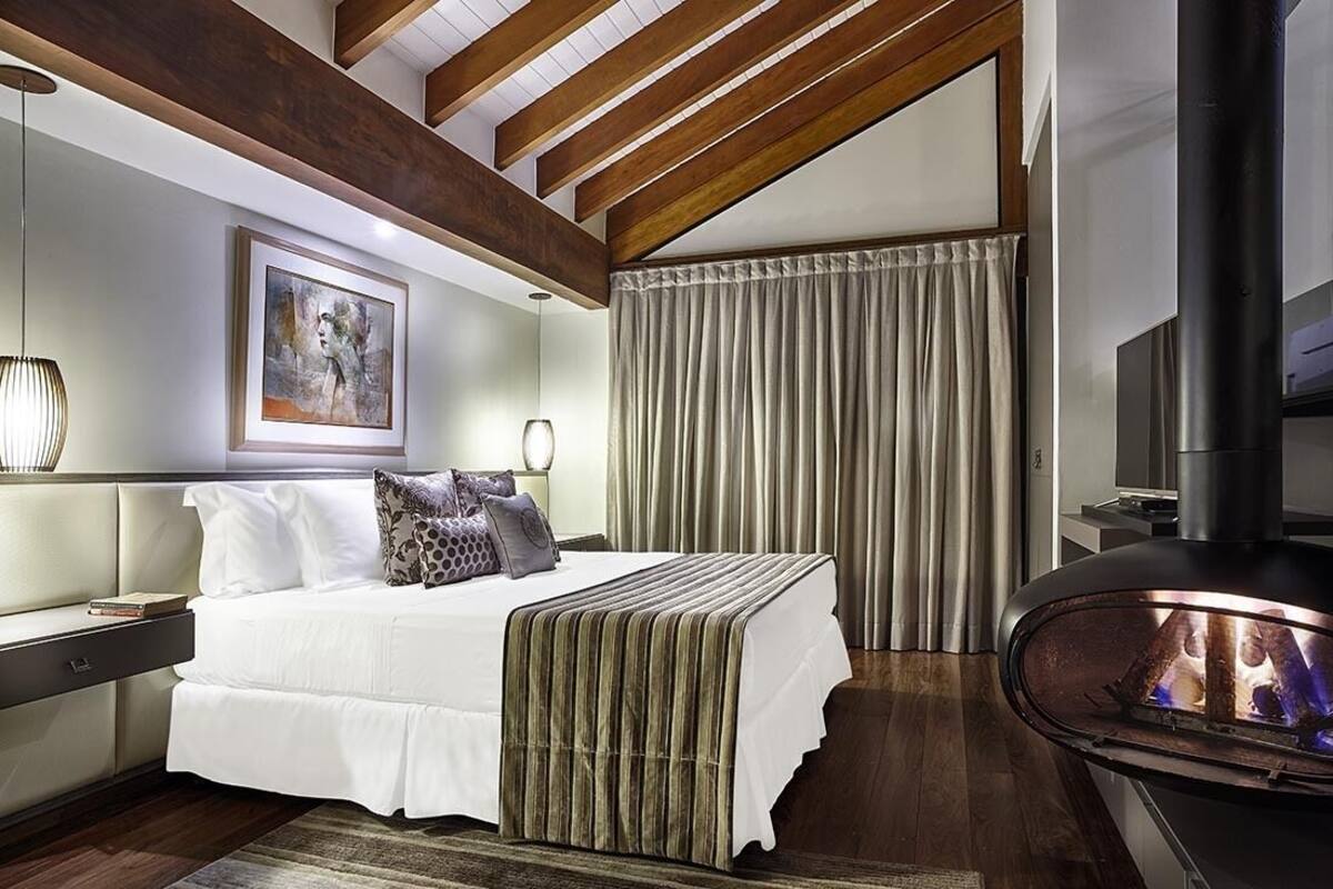 Une chambre moderne avec un grand lit, une cheminée et un tableau au mur.