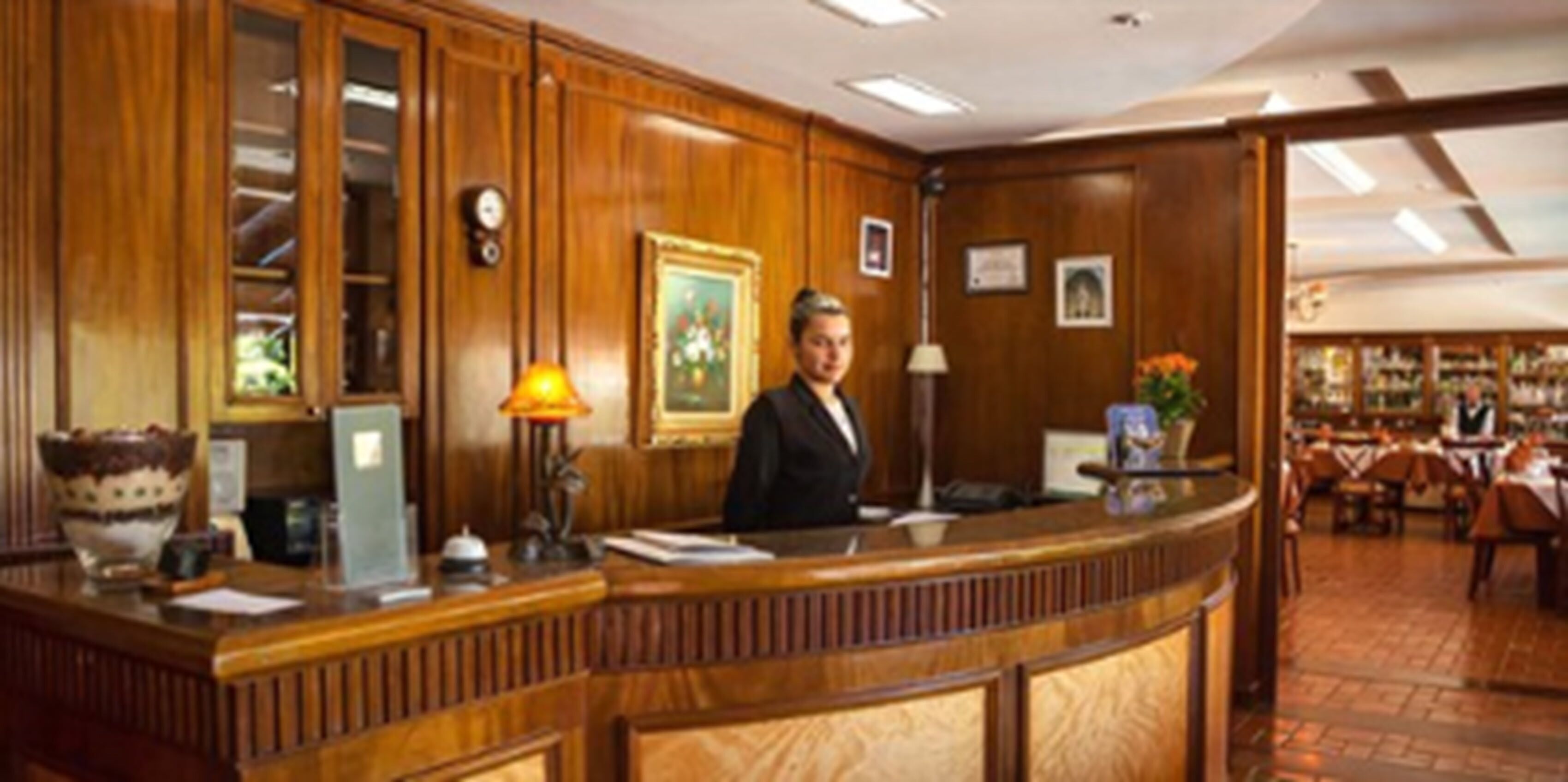 A wooden reception desk with a framed picture, a clock, and a lamp.