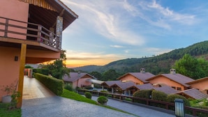 Un resort con varias construcciones, un sendero pavimentado y una vista panorámica de colinas.