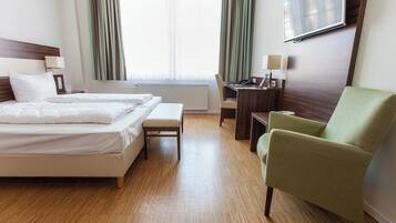 A hotel room with two beds, a desk, a chair, and a TV on the wall.