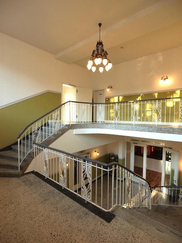 Un interior de varios niveles con una escalera, una araña y una zona de recepción.
