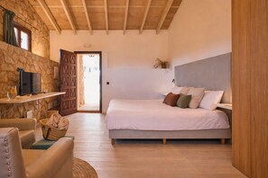 Un dormitorio con una cama, un televisor en un estante, una pared de piedra y un techo de madera.