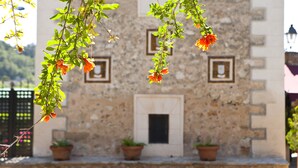 A stone building with a door and windows, potted plants on the ground, and hanging flowers. - S'Hort de Son Caulelles - Adults Only (Marratxi)