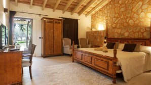 A bedroom with a large bed, wooden wardrobe, and a stone wall.