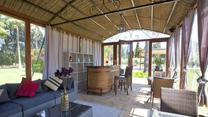 A covered outdoor seating area with a sofa, chairs, a table, and a bar.