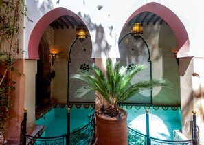 A courtyard with a tiled pool, arches, and a potted plant. - Riad Anabel (Marrakech)