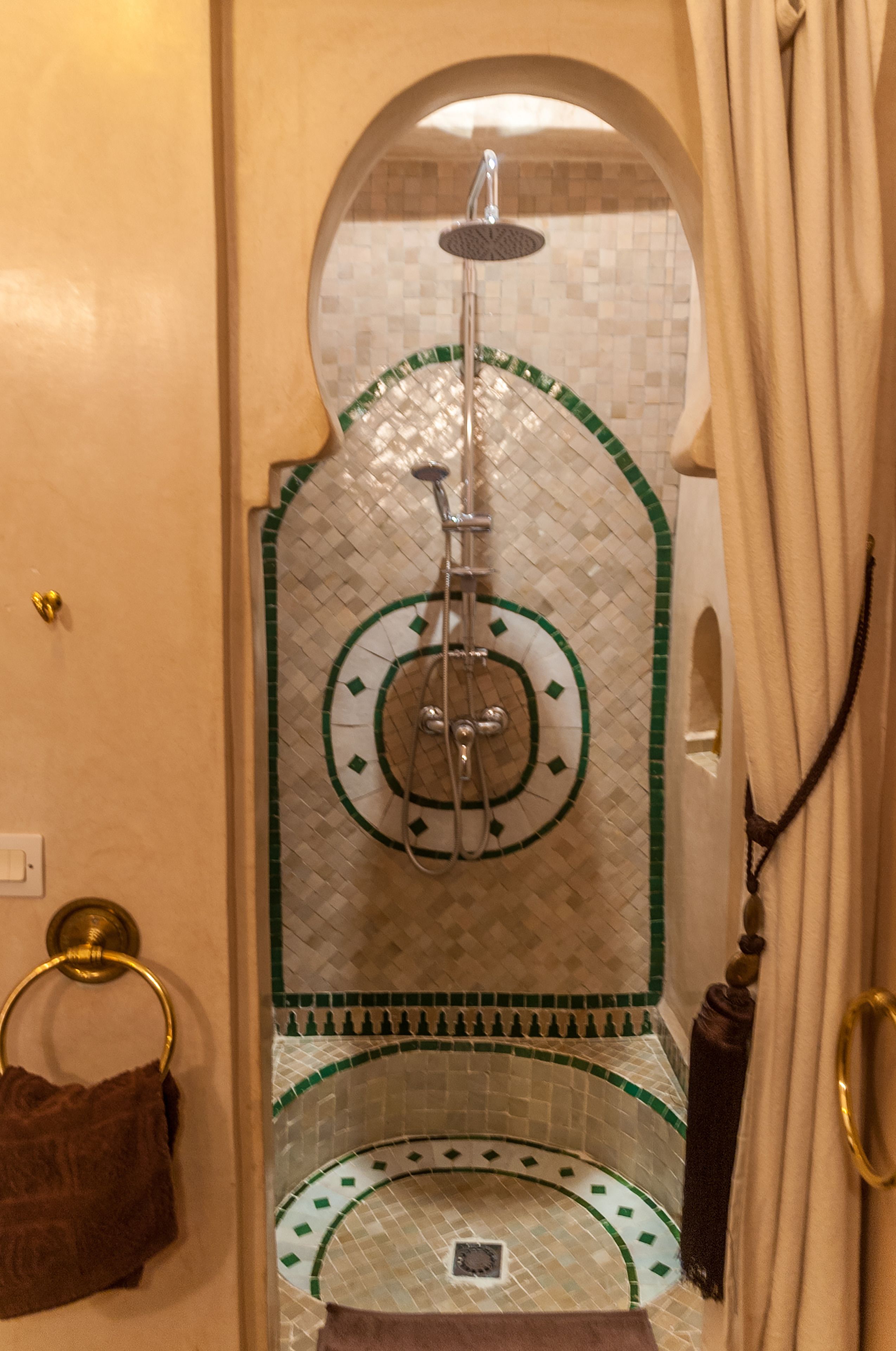 A bathroom with a shower, tiled walls, and a towel ring.