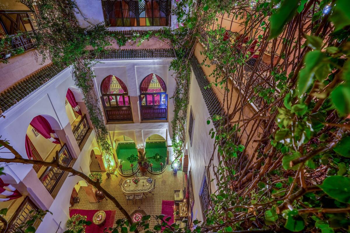 An indoor courtyard with a central seating area, surrounded by arches and greenery.