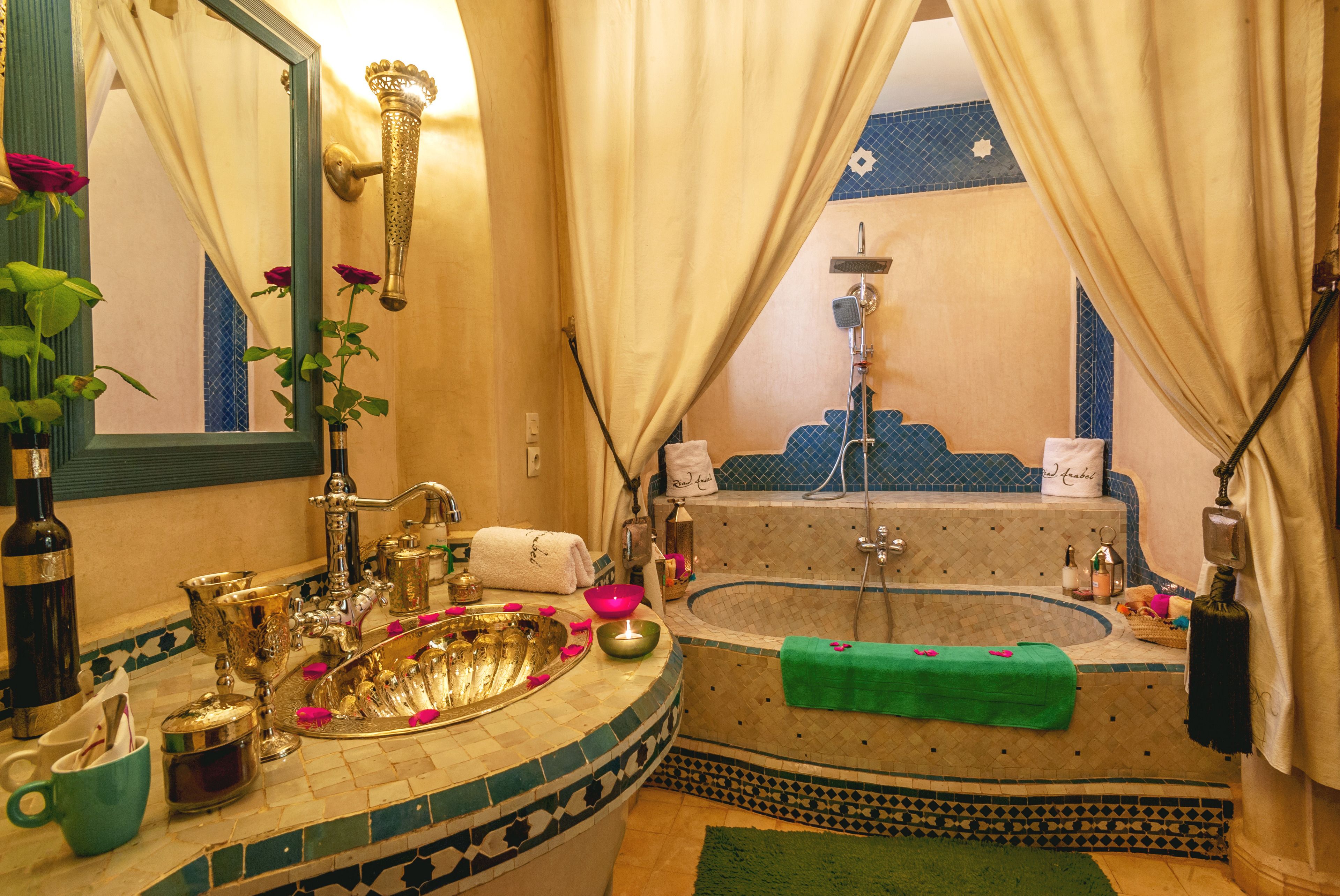 A bathroom with a large bathtub, a sink with ornate fixtures, and a mirror with a decorative frame.