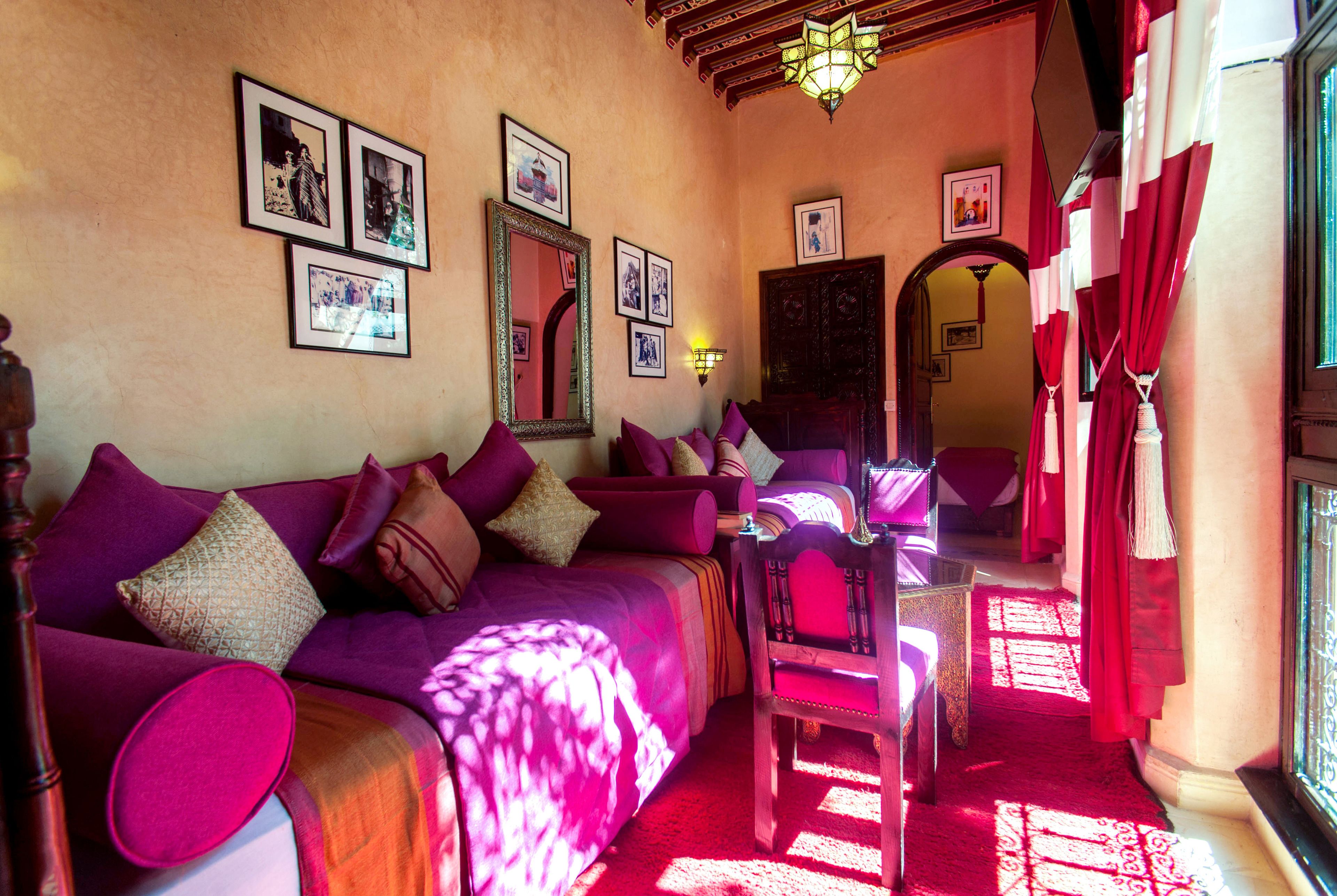 A cozy room with a purple sofa, a wooden chair, and a mirror on the wall.