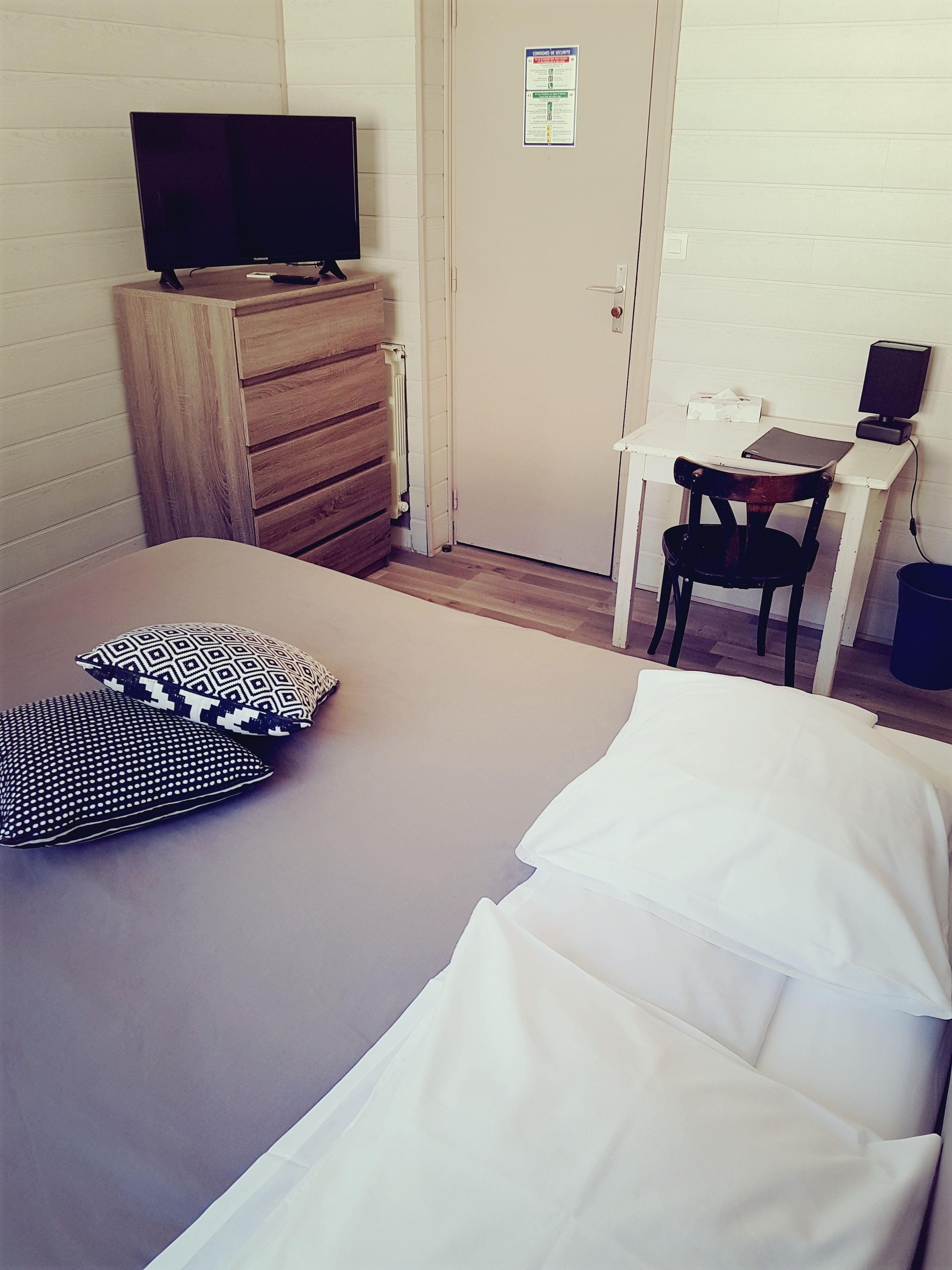 Une chambre d’hôtel avec un lit, un bureau et une chaise, une télévision et un radiateur.