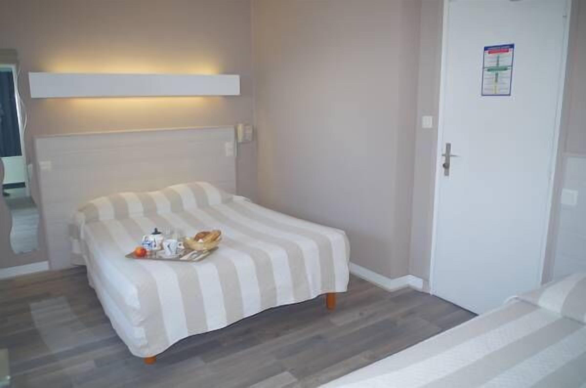 A single bed with a striped bedspread, a bedside table with a lamp, and a door with a poster.