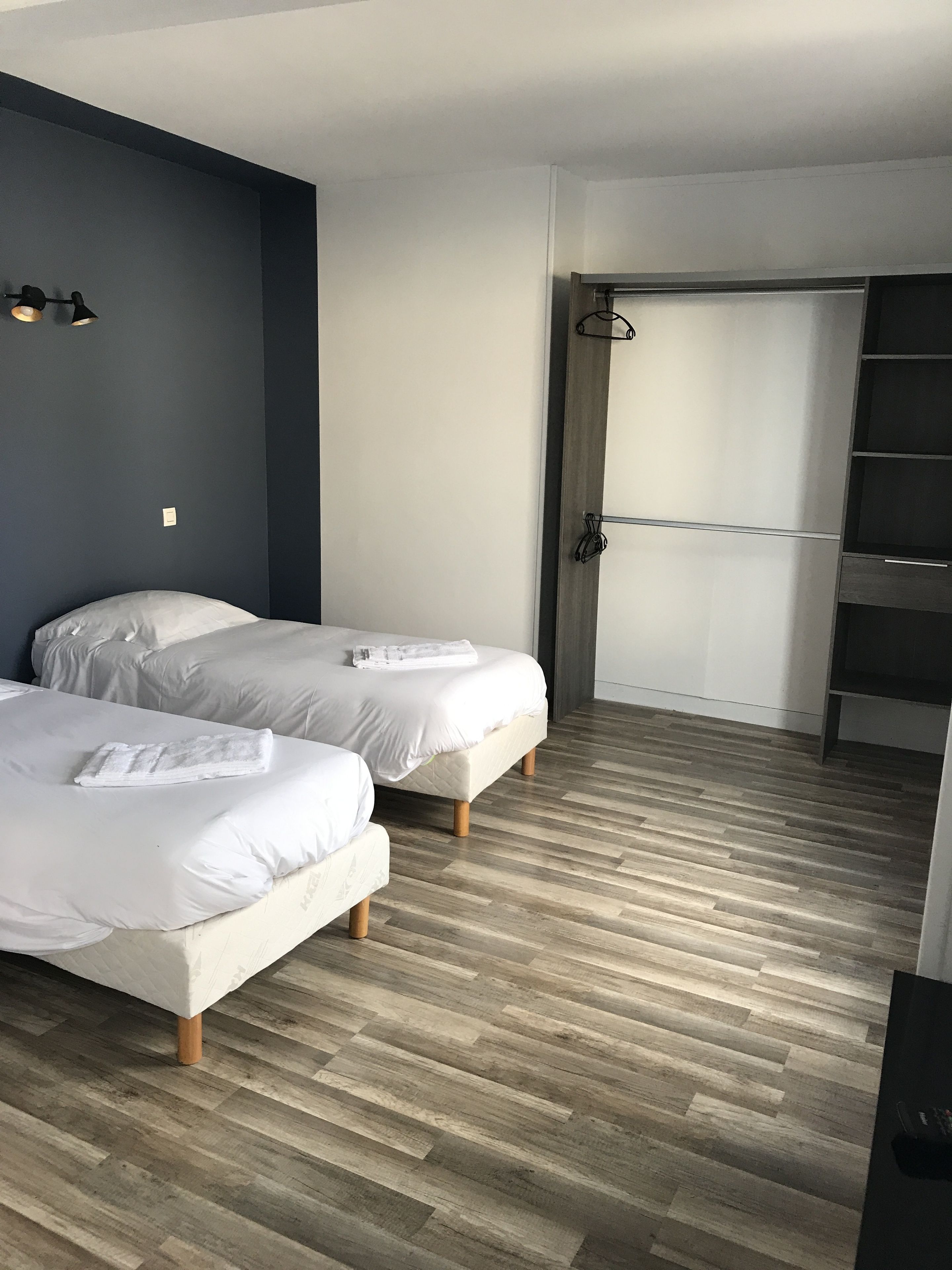 Quarto moderno com duas camas, piso de madeira e armário embutido.
